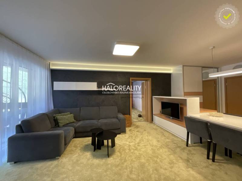 Living room in a 3-room apartment with a grey sofa and a television.