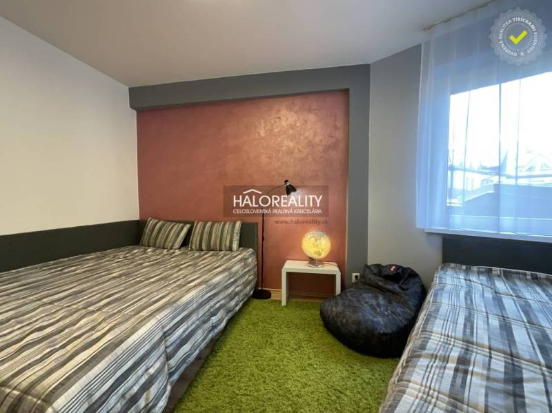 A bedroom in a 3-room apartment with two beds, a lamp, and a green carpet.