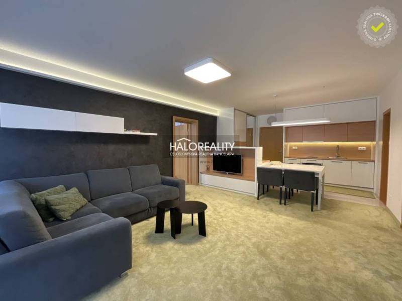 Living room with a sofa, table, and open kitchen in a 3-room apartment.