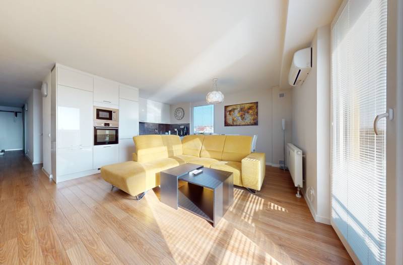 Living room in a three-room apartment with a comfortable sofa and a kitchen unit.
