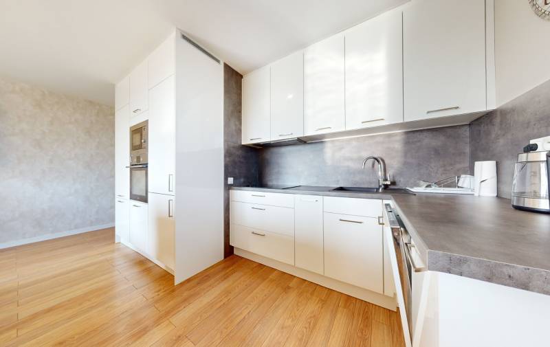 A kitchen in a 3-room apartment with white cabinets and wooden flooring.