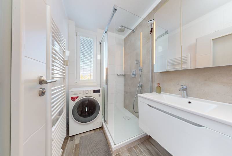 Bathroom with a shower, washing machine, and sink in a 3-room apartment.