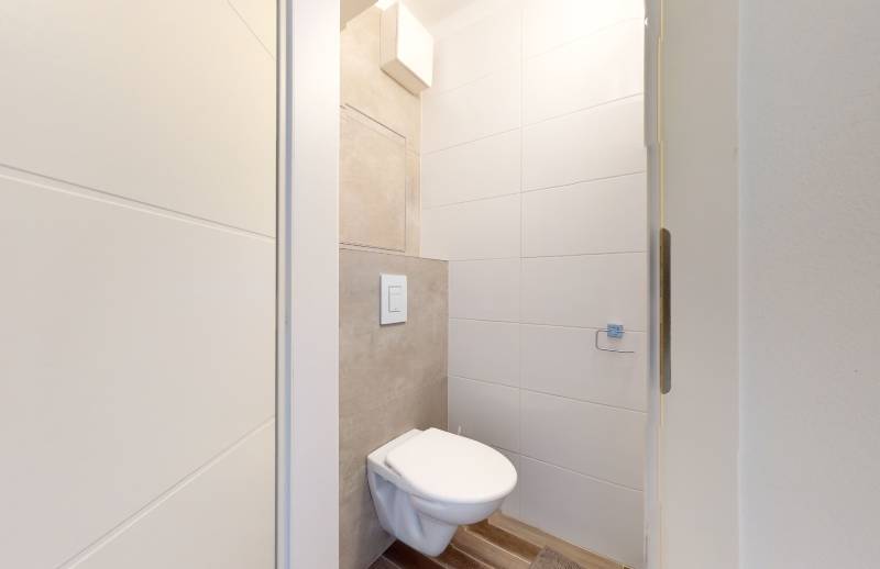 A bathroom in a 3-room apartment with a toilet and tiles on the walls.