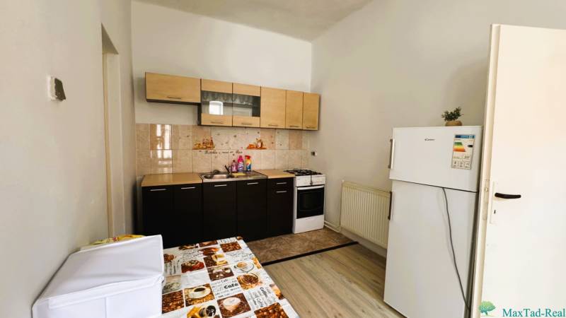 A kitchen with tiles, a kitchen unit, a stove, and a refrigerator in a family house.