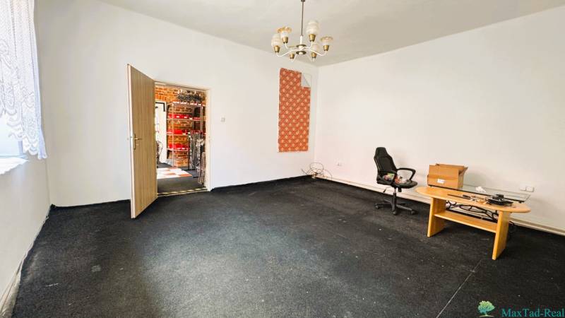 A room in a family house with a carpet, a table, a chair, and an open door.