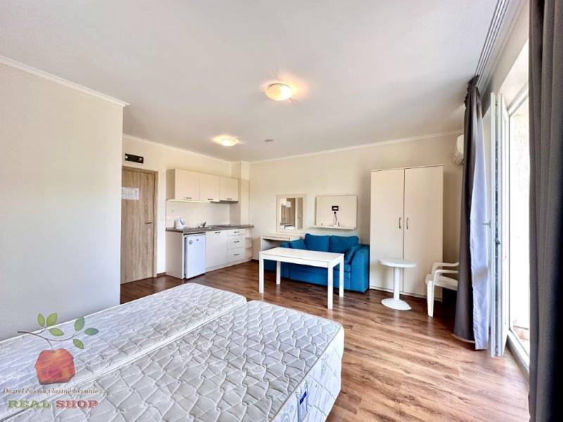 Recreational apartment with beds, a kitchenette, a blue sofa, and a table with two chairs.