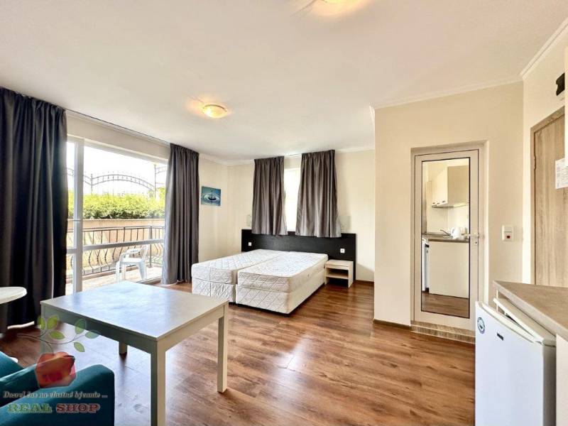 Interior of a holiday apartment with beds, a balcony, and a kitchenette, ideal for a vacation.
