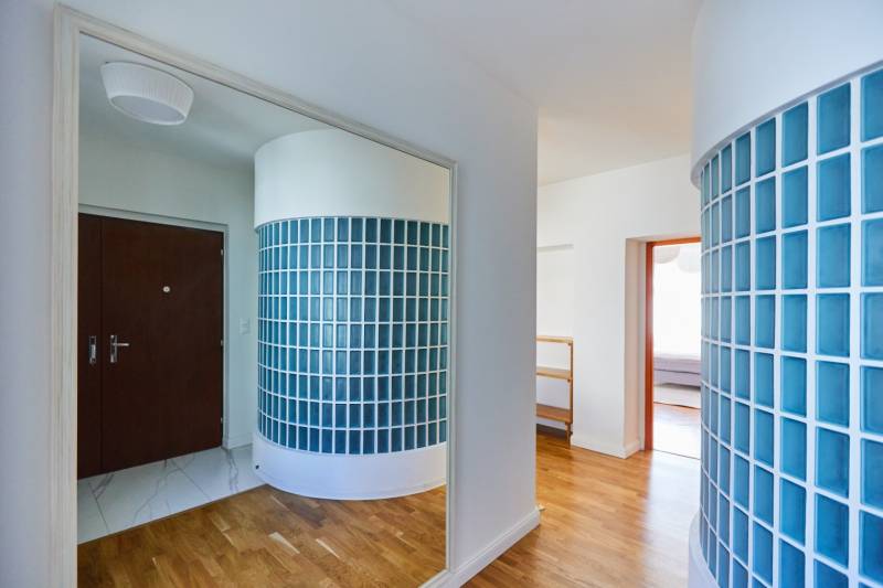 Entrance hallway with blue glass blocks and wooden flooring in a 4-room apartment.