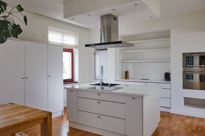 A kitchen in a 4-room apartment with an island, wooden flooring, and built-in appliances.