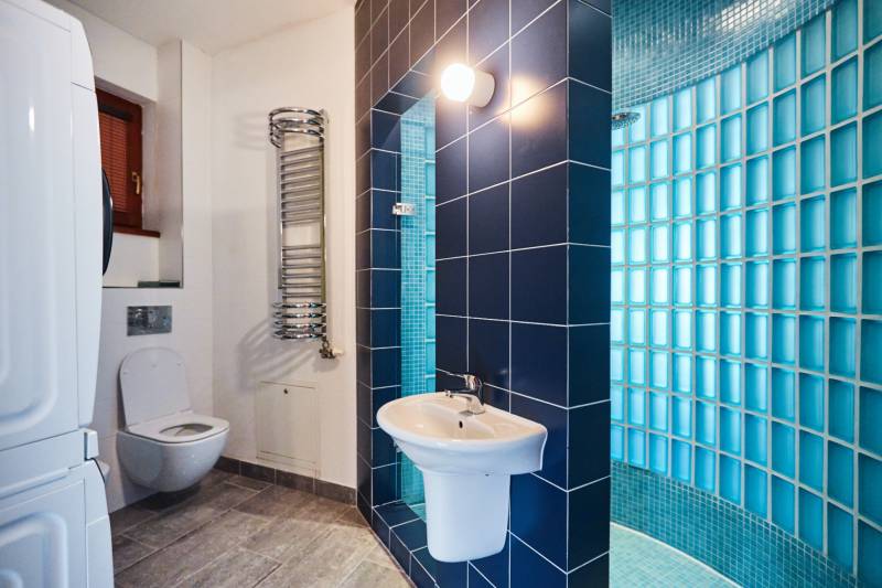 Bathroom with toilet, sink, shower, and washing machine in a 4-room apartment.