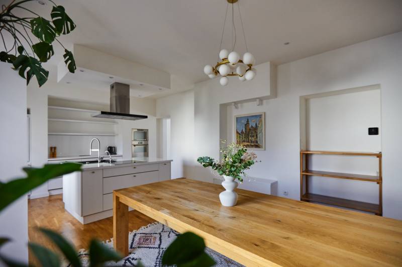 The kitchen of a 4-room apartment with a wooden table, a chandelier, and a decorative vase.