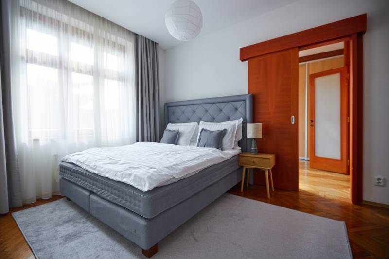 Bedroom in a 4-room apartment with a bed, nightstand, and wooden door.