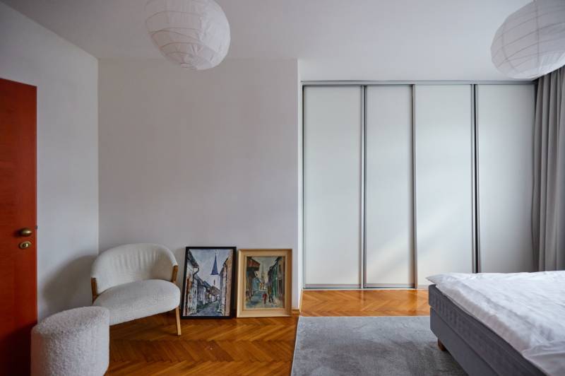 Bright bedroom with a wardrobe, armchair, and paintings in a 4-room apartment.