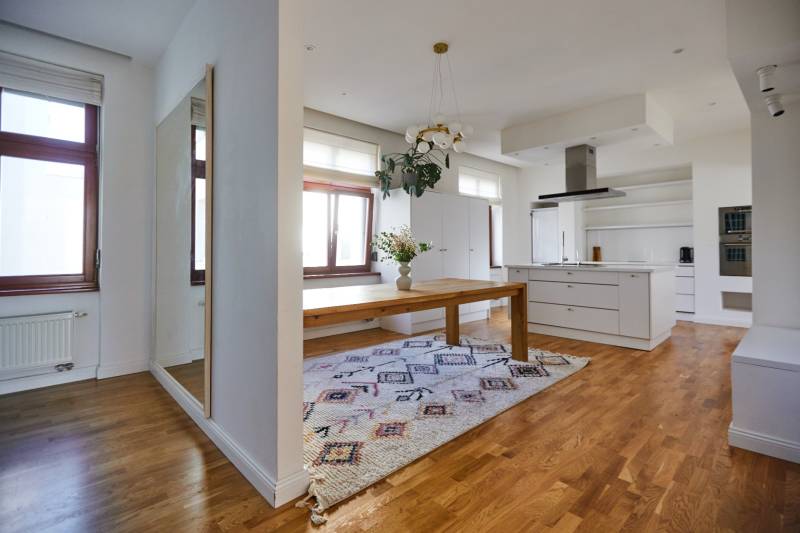 Interior of a 4-room apartment with wooden flooring, kitchen, and dining table.