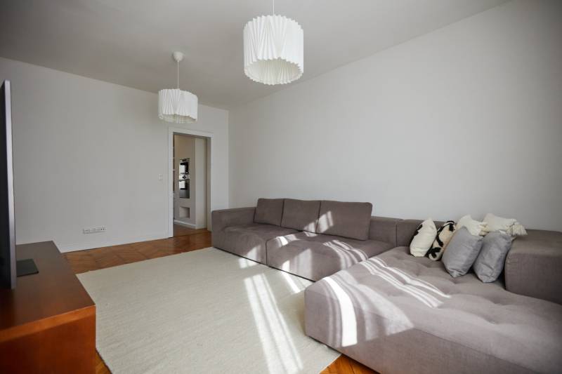 Living room with a large gray sofa and white lights in a 4-room apartment.