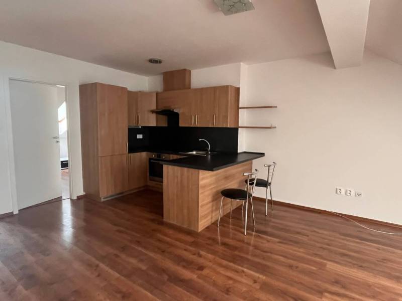 The kitchen in a 3-room apartment with wooden floors, a black countertop, and two chairs.