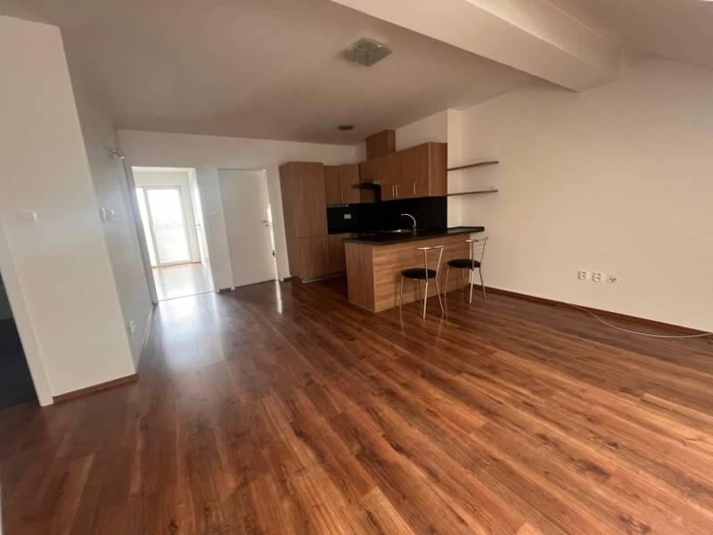 Interior of a 3-room apartment with wooden flooring and a kitchen unit with a bar.