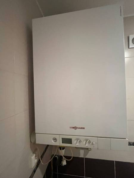 Gas boiler in the bathroom of a 3-room apartment with white tiles.
