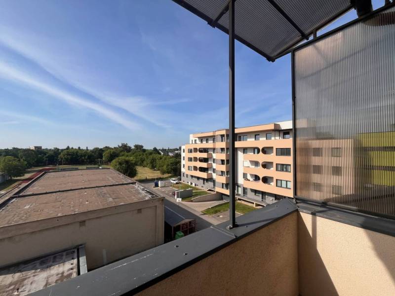 The view from the balcony of a 3-room apartment in Dunajská Streda to the surrounding buildings and greenery.