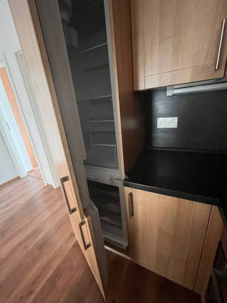 A kitchen in a 3-room apartment with a wooden floor and a built-in refrigerator.