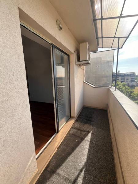 A balcony of a 3-room apartment with a view of the surroundings, glass doors, air conditioning.