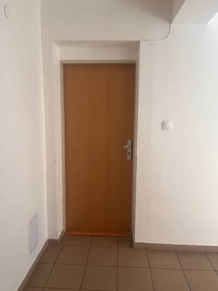 White walls and wooden doors in a 3-room apartment, light tiles on the floor.