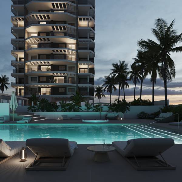 A pool by a lit 3-room apartment in Calpe surrounded by palm trees in the evening.
