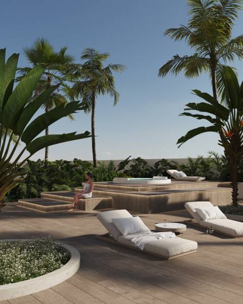 Tropical terrace with loungers, palm trees, and a hot tub in a 3-bedroom apartment in Calpe.