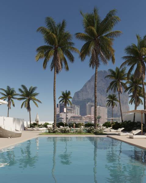 Luxury pool in Calpe surrounded by palm trees with a view of the city and rocks.
