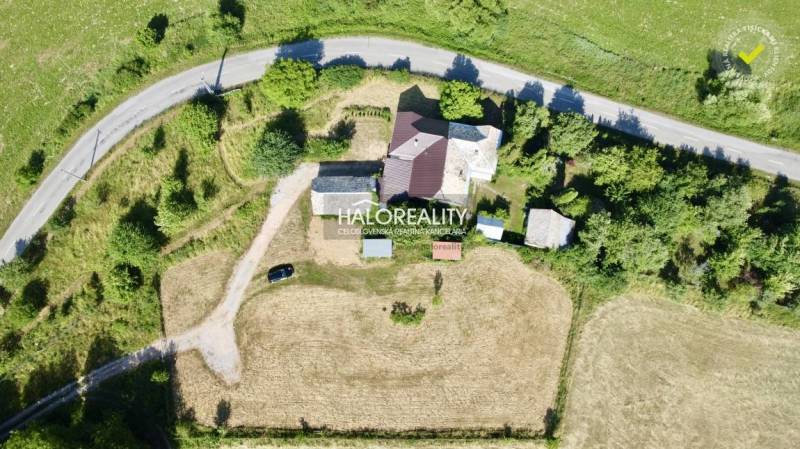 Aerial view of a family house in Ploské surrounded by a grassy plot and a road.