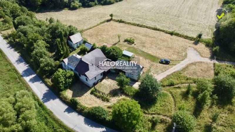 A family house in Ploské, surrounded by trees and agricultural landscape near the main road.