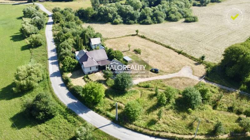 A family house in the village of Ploské surrounded by greenery and an access road.