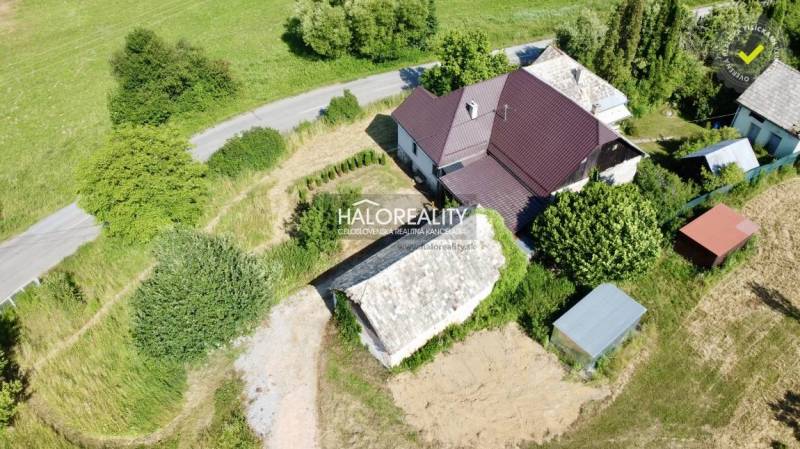 A family house in Ploské surrounded by greenery and an access road by the house.