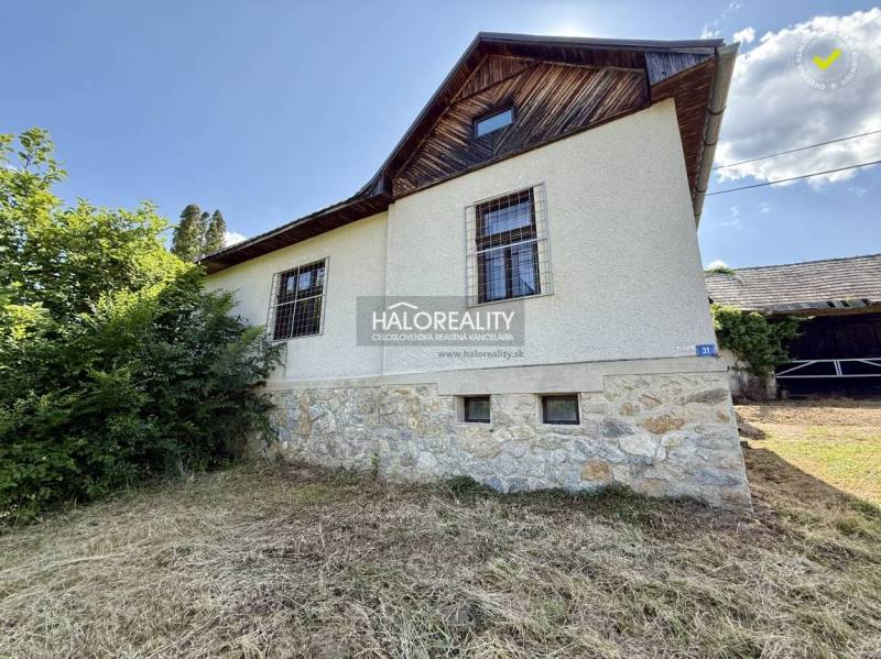 A family house in Ploské with a stone facade and green surroundings under a blue sky.