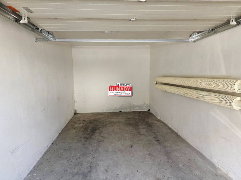 The interior of a garage with an open door and hooks on the wall.