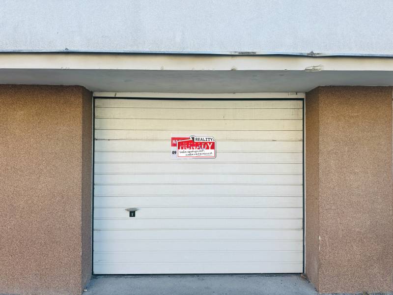 White garage door on Štefánik Square in Spišská Nová Ves with the sign for sale.