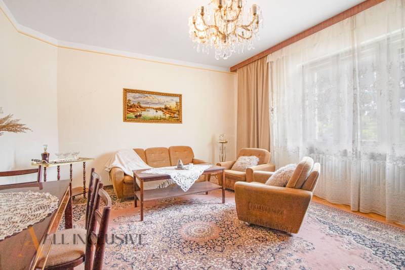 Living room in a family house with a chandelier, sofa, carpet, and curtains.