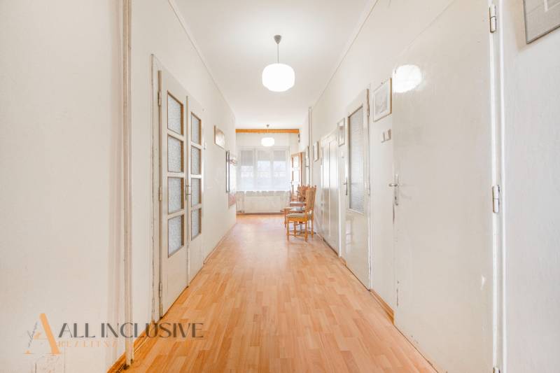 A long hallway with light wooden flooring in a family house.