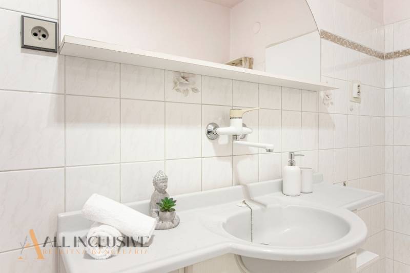 Family house bathroom with a sink, socket, and decoration on the shelf.