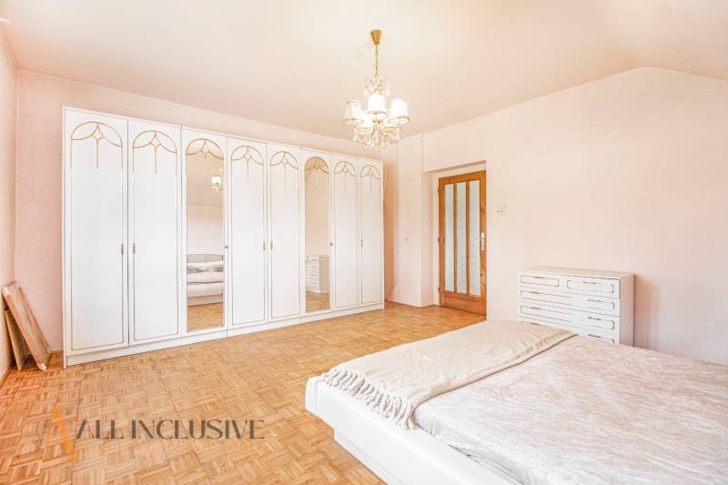 The master bedroom in the family house is adorned with spacious mirrored wardrobes and simple lighting.