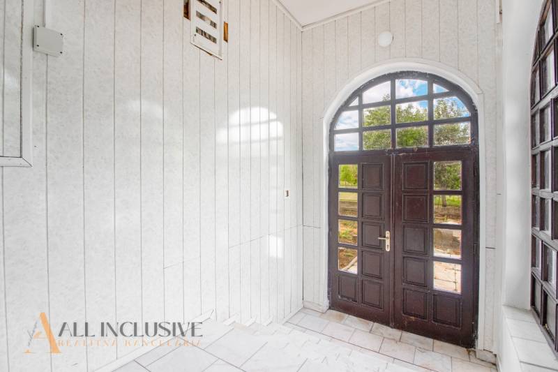 Interior of a family house with entrance doors with glazing, white walls, and tiles.