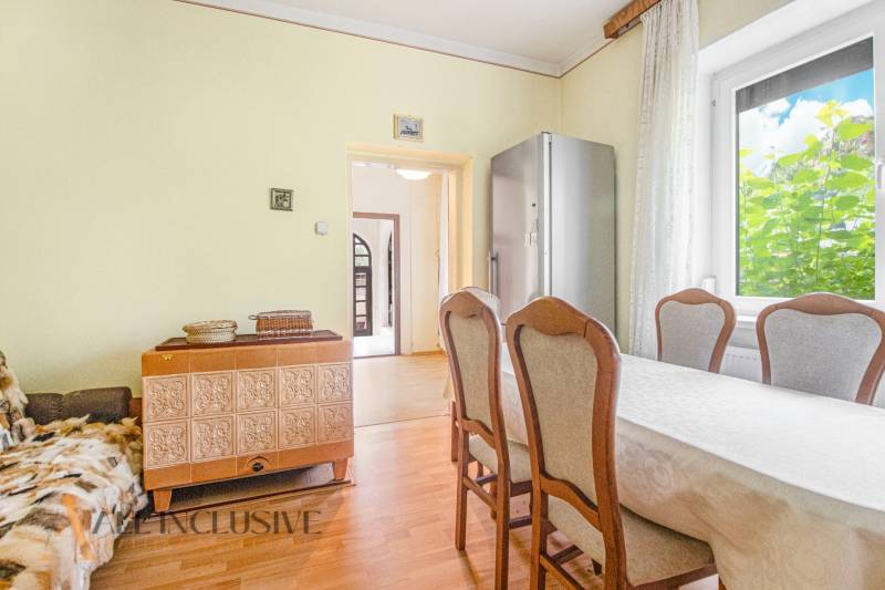 Dining area with a tiled stove and a view of the hallway in a family house.