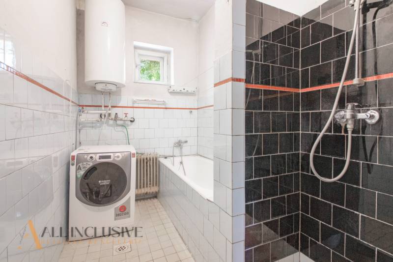 A bathroom in a family house with a shower, a washing machine, and a bathtub, tiled with tiles.