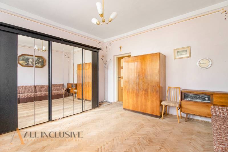 An interior with wooden furniture, a mirrored wardrobe, and a sofa in a family house.