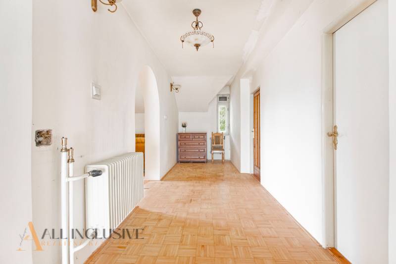 A spacious hallway with wooden flooring and furniture in a family house.