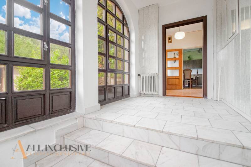 A bright hallway with large windows and an entrance to the living room in a family house.