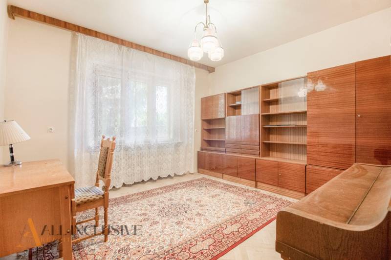 A room in a family house with a carpet, a wardrobe, and a table, illuminated by daylight.