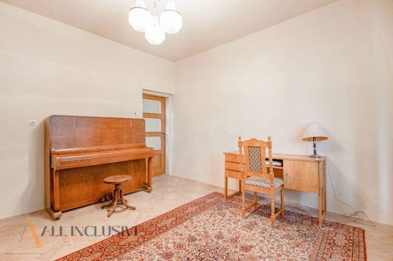 Interior of a family house with a piano, carpet, writing desk, and chair.