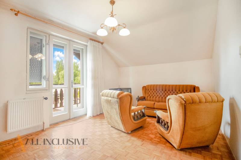 Living room with brown furniture, a sofa, and a French window in a family house.