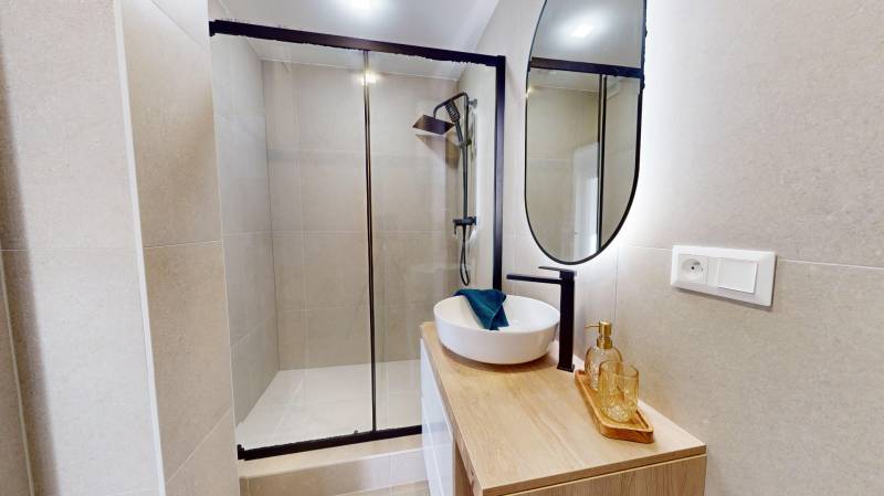 Bathroom with a shower, a countertop sink, and a mirror in a 3-room apartment.